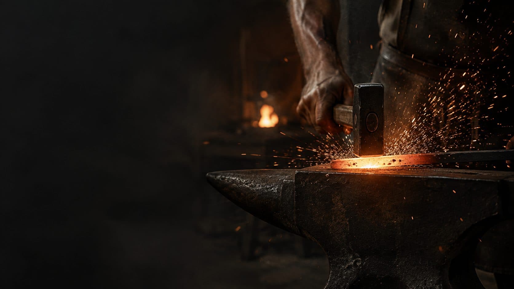 A blacksmith's hammer falling on steel glowing orange on the anvil